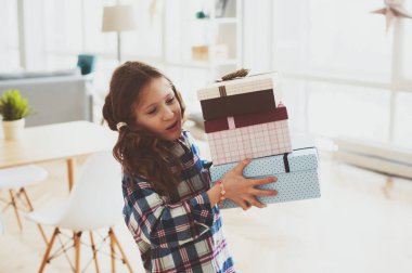 hazırlama veya pek çok doğum günü hediyesi almak mutlu bir çocukluk kız. Çocuk evde hediyeler yığını ile