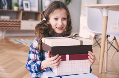 hazırlama veya pek çok doğum günü hediyesi almak mutlu bir çocukluk kız. Çocuk evde hediyeler yığını ile