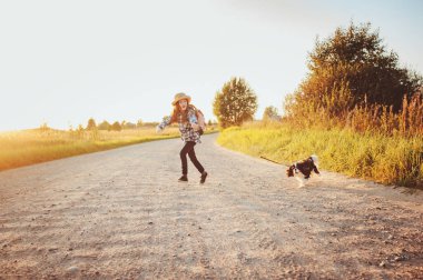 Mutlu kız çocuğu köpeğiyle yaz tatilinin tadını çıkarıyor, güneşli çayırlarda yürüyor ve oynuyor. Seyahat etmek, yeni yerler keşfetmek ve kırsal yaşam kavramı
