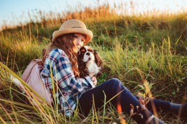 Mutlu kız çocuğu köpeğiyle yaz tatilinin tadını çıkarıyor, güneşli çayırlarda yürüyor ve oynuyor. Seyahat etmek, yeni yerler keşfetmek ve kırsal yaşam kavramı