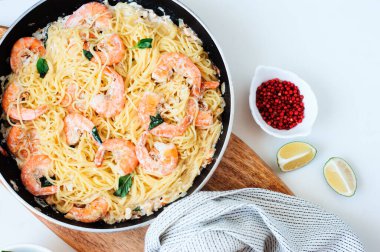 Tavanın üst görüntüsü, kremalı fesleğenli, pembe biberli, limonlu, beyaz arka planlı makarna. 