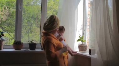 Happy Mom with baby caring for houseplants and dancing