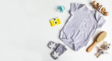 Beyaz arka planda bebek aksesuarları olan bir kompozisyon. Bebek partisiyle ya da bebek kıyafetleri, oyuncaklar, saç fırçası ile yeni doğan bebek odası konseptiyle ilgili cinsiyet ayrımı yok. Düz yatış ve üst manzara. Boşluğu kopyala