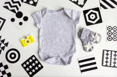 Beyaz arka planda bebek aksesuarları olan bir kompozisyon. Bebek partisiyle ya da bebek kıyafetleri, oyuncaklar, Vizyon Geliştirme kontrast kartlarıyla yeni doğan bebek odası konseptiyle ilgili cinsiyetsiz tema. düz ve üst görünüm.