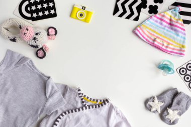 Beyaz arka planda bebek aksesuarları olan bir kompozisyon. Bebek partisiyle ya da bebek kıyafetleri, oyuncaklar, Vizyon Geliştirme kontrast kartlarıyla yeni doğan bebek odası konseptiyle ilgili cinsiyetsiz tema. Düz yatış ve üst manzara. Boşluğu kopyala