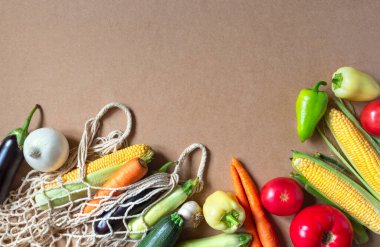 Eko arka planında taze çiğ sebzeler ve ağ alışveriş torbası. Sağlıklı yiyecekler. Vejetaryen, organik gıda. Boşluk arkaplanını, üst görünümü, düzlüğü kopyala