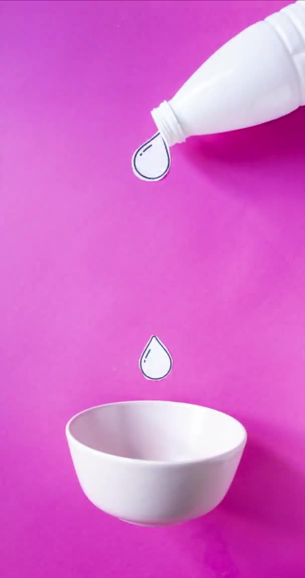 ボトルから注ぐミルクと面白いストップモーションアニメーション ピンクの背景に朝食のためにボウルに落ちるコーンフレーク — ストック動画