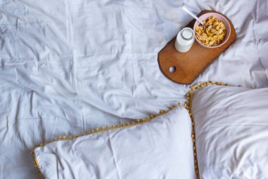 Tahta masada mısır gevreği ve sütle yatakta basit bir kahvaltı. Sarı ve beyaz renkler. Düz yat, boşluğu kopyala