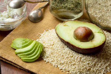 Taze kesilmiş avokado, yumuşak peynir ve ahşap arka planda otlar. Ketogenik diyet yemek planı için gıda malzemesi hazırlama, sağlıklı beslenme yaşam tarzı programı. Seçici odak