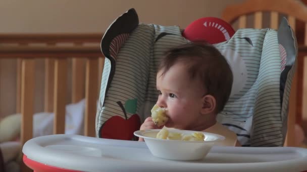 Niedliches Baby, das zum ersten Mal zu Hause Blumenkohl isst. Gesunde Kinderernährung, Baby zuerst solide ernähren, Baby 7 Monate im Hochstuhl frisst sich selbst, selbst ernähren — Stockvideo