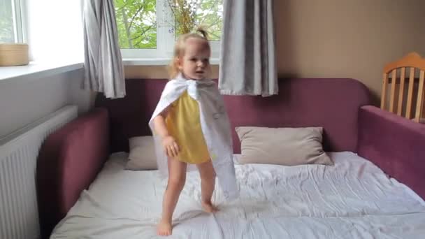 Linda niña saltando y cayendo en la cama — Vídeo de stock