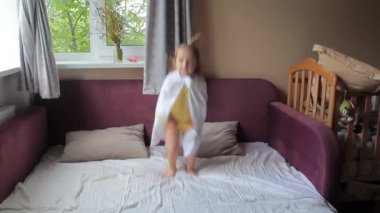 Tatlı küçük kız zıplıyor ve yatağa düşüyor.
