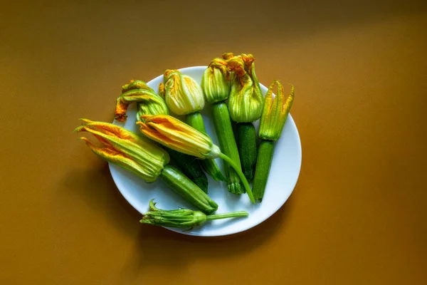 Zucchine Con Fiori Placca Bianca Sullo Sfondo Marrone Caramello Posa — Foto Stock