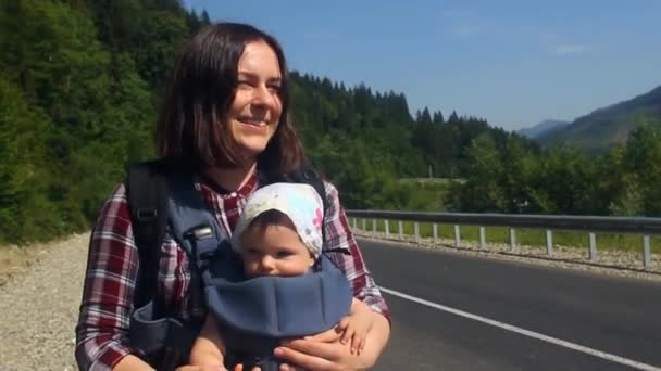 登山道で赤ちゃんヒッチハイクをする旅行者のお母さん. — ストック動画