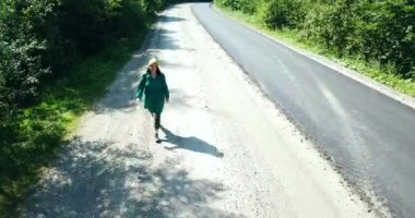 Ormanın ortasında, boş bir yolda tek başına yürüyen kadınlar.