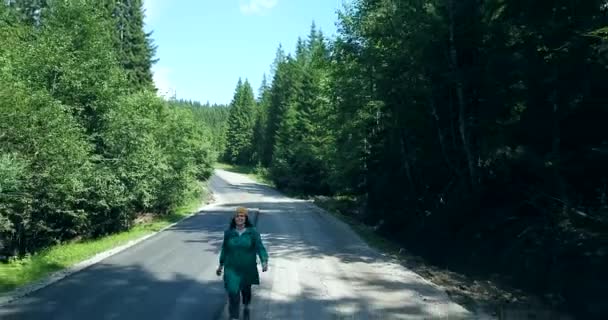 Vrouwen die alleen in het midden van de bosweg lopen en weglopen van de auto — Stockvideo