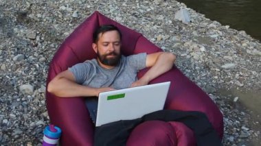 Genç Kafkasyalı serbest çalışan Laptop bilgisayarı üzerinde çalışırken doğanın hareketliliğinin keyfini çıkarıyor..