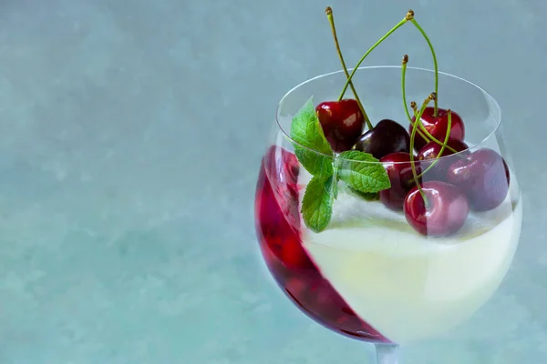 Kirazlı şarap bardağında özel tatlı. Gri arkaplanda böğürtlenli panna cotta.