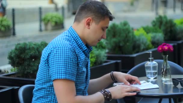 Turysta z mapą siedzącą w ulicznej kawiarni — Wideo stockowe