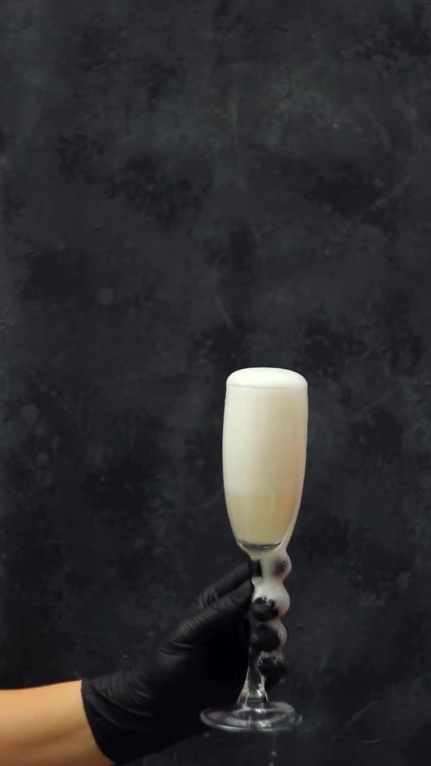 A hand in a black medical glove holding glass of champagne. vertical view orientation — Stock Video