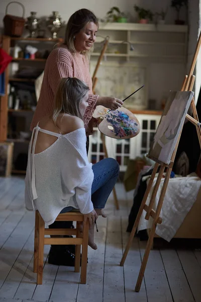 Nauczyciel uczy młodą dziewczynę do malowania na płótnie — Zdjęcie stockowe