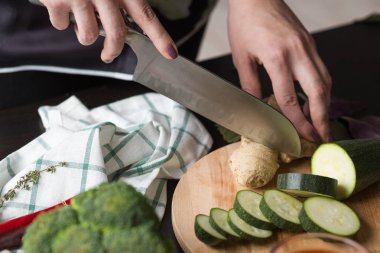 Kız sebze mutfakta bir bıçakla keser. Önden Görünüm