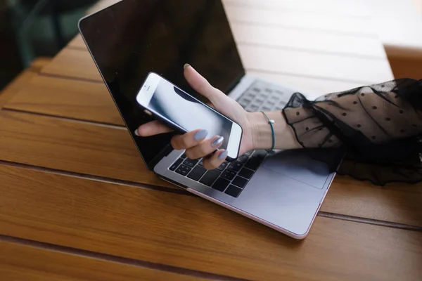 Serbest çalışan bir kız, bir çatı katında dizüstü bilgisayar ve telefonla çalışıyor.