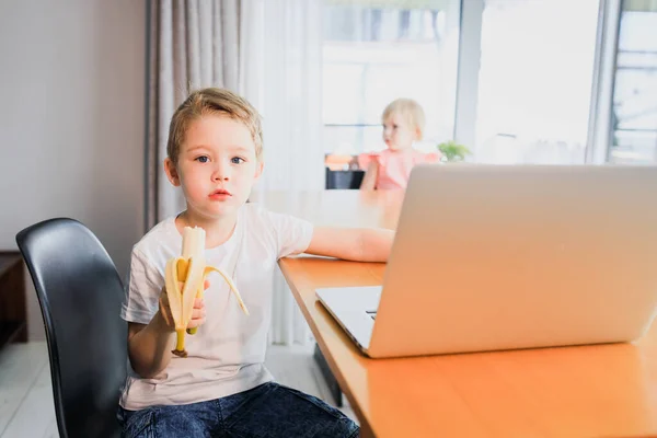 Small smiling kids brother and sister laugh and play laptop, communicate video conference chatting.