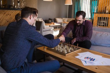 Erkekler modern bir tasarıma sahip şık bir çatı katında satranç oynarlar.