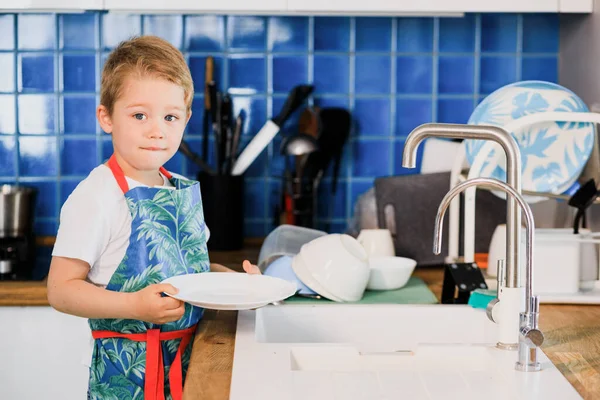 Bir çocuk ailesinin bulaşıkları yıkamasına yardım eder.