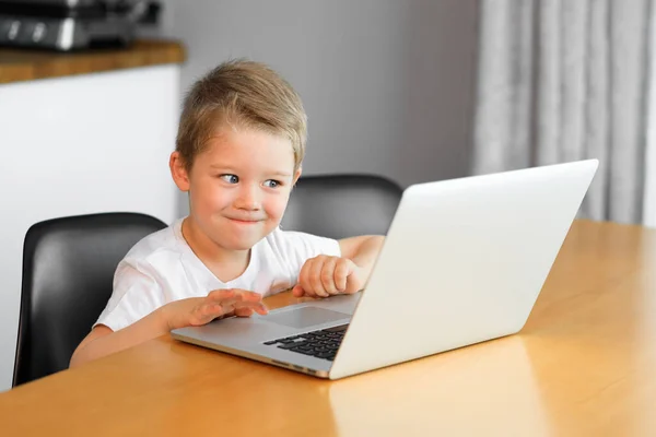 Un niño pequeño ve un video educativo en un nuevo portátil Fotos De Stock Sin Royalties Gratis