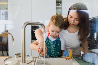 Anne ve oğul birlikte bulaşık yıkıyorlar.