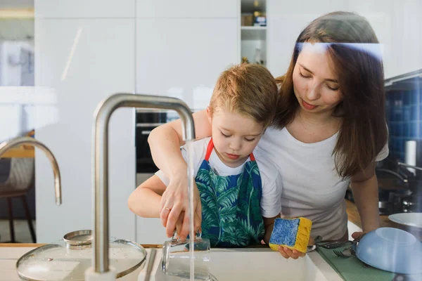 Mother and son wash dishes together