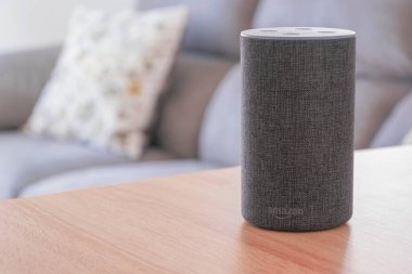 Koyu gri Amazon Alexa Echo bir salonda, ahşap bir masada. Düzenleyicinin içeriği için boş kopyalama alanı.