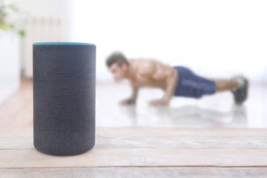 Alexa Echo artı fitness yeteneği olan bir cihaz ve evde şınav çeken bir adam. Düzenleyicinin metni için boş kopyalama alanı