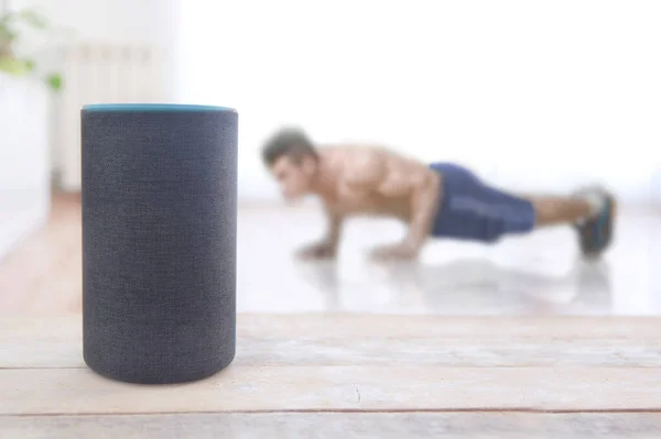 Alexa Echo artı fitness yeteneği olan bir cihaz ve evde şınav çeken bir adam. Düzenleyicinin metni için boş kopyalama alanı
