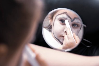 Genç bir kız soyunma odasında makyaj yapıyor. Gezgin palyaço çocuk.. 