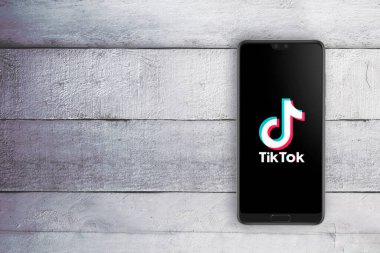 TikTok uygulaması akıllı telefondan çalışıyor. Editörün içeriği için boş kopya alanı olan beyaz tahta masa. Yukarıdan aşağı çekim.