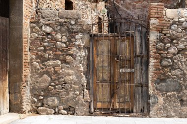Kırsal bir binada taş duvar ve hasarlı eski ahşap bir kapı. İspanya, Akdeniz ve Güney Avrupa ülkesinde seyahat hedefi geçmişi.