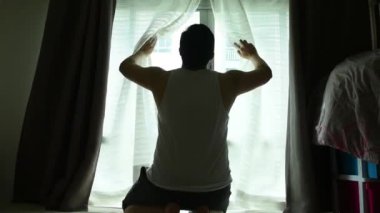 Coronavirus salgınını korumak için sosyal uzaklık kavramı karşı odadaki arkadaşla telefon görüşmesi yaparak apartman dairesinin penceresinden sabah güneşinin tazeliğini geçerek