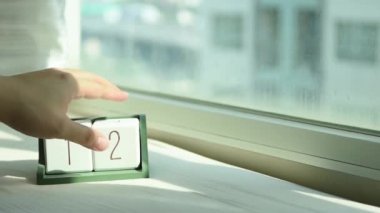 Yeni gün için el değiştiren beyaz ahşap takvim bloğu. Tatlı pembe yatakta, modern pencereden gelen taze sabah ışığı, konsept hayat motivasyonunu başlatır.