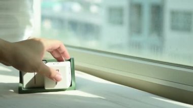 Yeni gün için el değiştiren beyaz ahşap takvim bloğu. Tatlı pembe yatakta, modern pencereden gelen taze sabah ışığı, konsept hayat motivasyonunu başlatır.