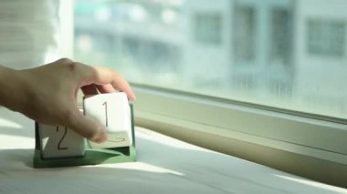 Yeni gün için el değiştiren beyaz ahşap takvim bloğu. Tatlı pembe yatakta, modern pencereden gelen taze sabah ışığı, konsept hayat motivasyonunu başlatır.