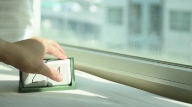 Yeni gün için el değiştiren beyaz ahşap takvim bloğu. Tatlı pembe yatakta, modern pencereden gelen taze sabah ışığı, konsept hayat motivasyonunu başlatır.