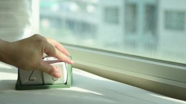 Yeni gün için el değiştiren beyaz ahşap takvim bloğu. Tatlı pembe yatakta, modern pencereden gelen taze sabah ışığı, konsept hayat motivasyonunu başlatır.