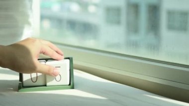 Yeni gün için el değiştiren beyaz ahşap takvim bloğu. Tatlı pembe yatakta, modern pencereden gelen taze sabah ışığı, konsept hayat motivasyonunu başlatır.