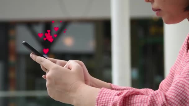 亚洲美女使用屏幕社交网络中带有红心图标的智能手机 在室外放松自己 不要戴口罩 但要保持与社会的距离 保持新的正常观念 精神健康 — 图库视频影像