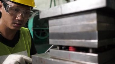 Mühendis kalıpları kontrol etmek için tablet kullanır ve metal levha imalatında güvenlik gözlüğü ve yeşil güvenlik üniforması ile kayıt ve hazırlık ekipmanlarını kaydetmek için ölür.