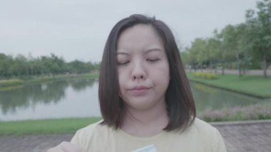 Erkek arkadaşı sıkıcı Asyalı kadını parkta maske takmaya zorladı. Rüzgâr kısa saçlara doğru esiyordu. Karantina koronavirüs hastalığından sonra tatilde gevşeme sarı tişörtü