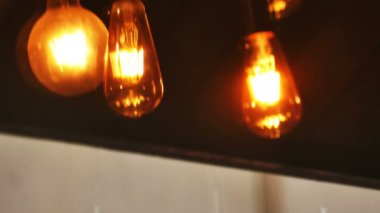 Eski bir ampulün 4K yansıması. Kahve dükkanının iç dekorasyonunda şiddetli yağmurla birlikte camdan sallanıyor. Yalnız insanları kavra ve dinlenmek için işten sonra rahatla.